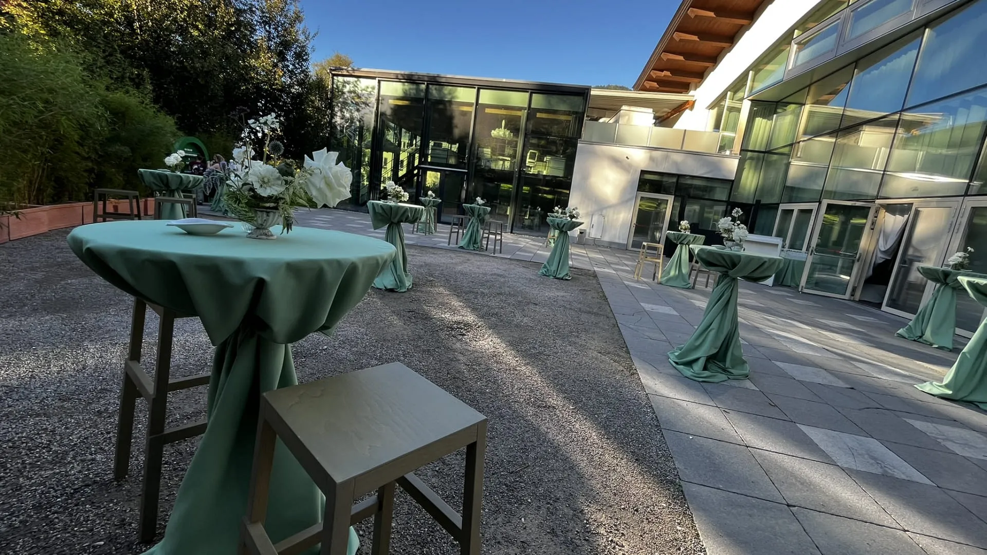Freiluftveranstaltung mit Tischen und Blumenarrangements.