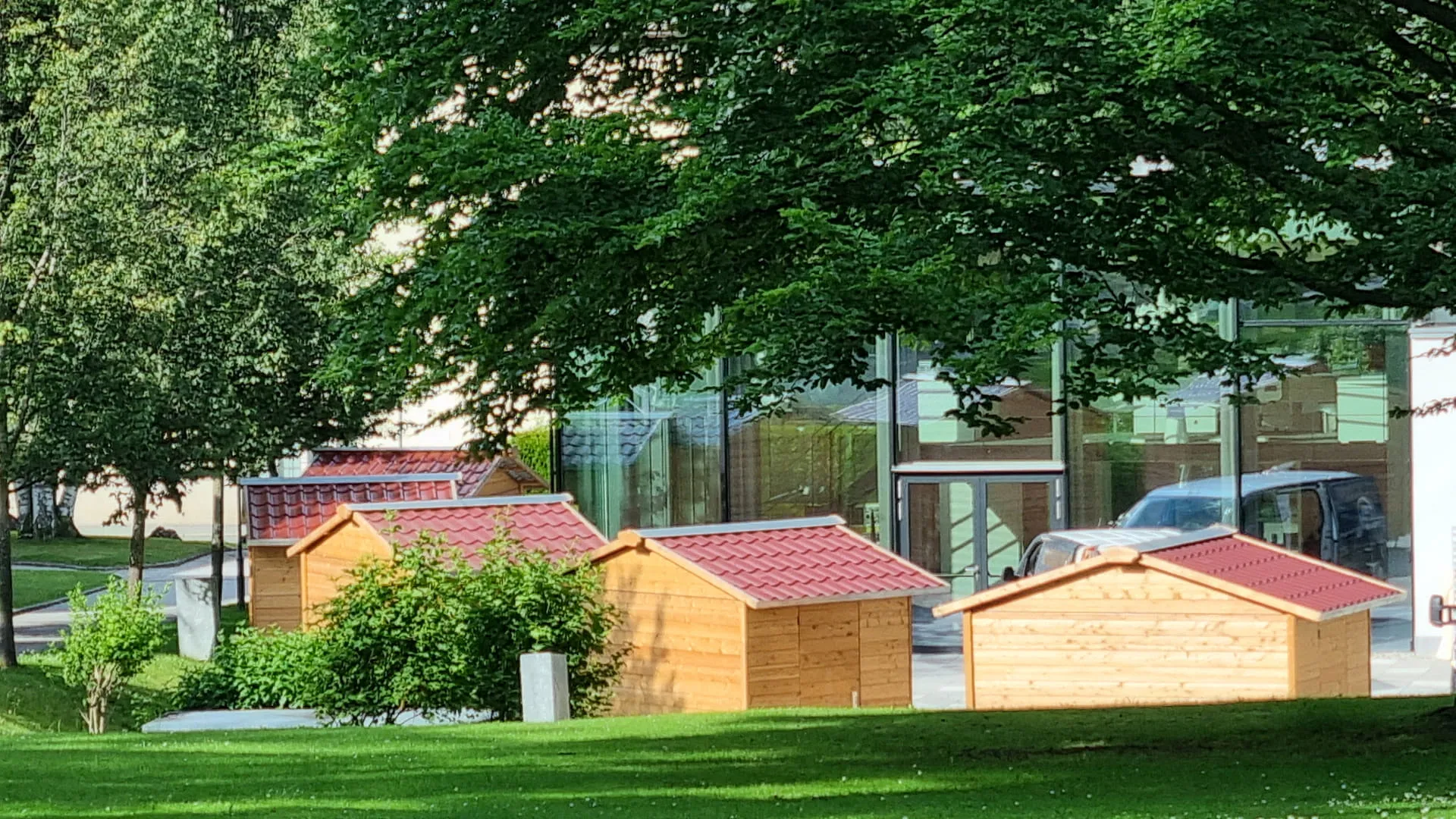 Holzhütten auf einer Wiese neben einem Gebäude