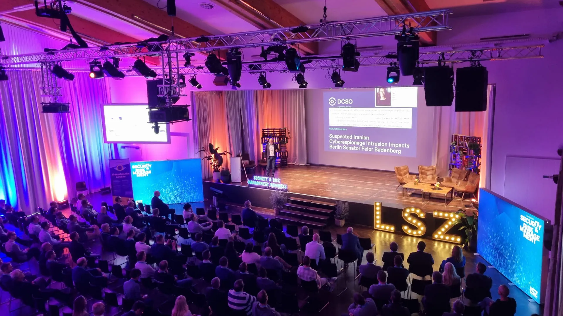 Publikum bei einer Konferenz mit Bühne und Bildschirmen