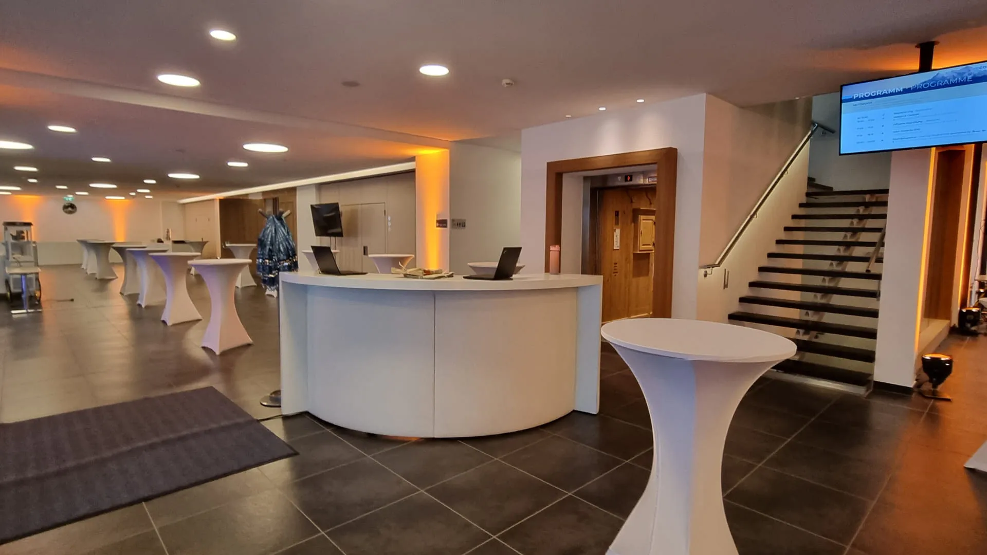 Moderne Empfangshalle mit Stehtischen und Treppe