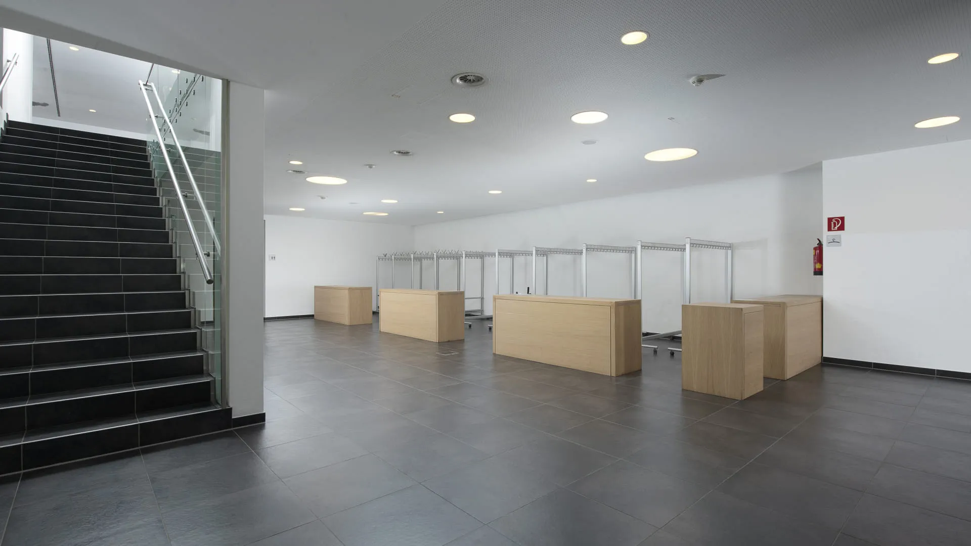 Helle Garderobe mit Holzflächen und Treppe im Hintergrund