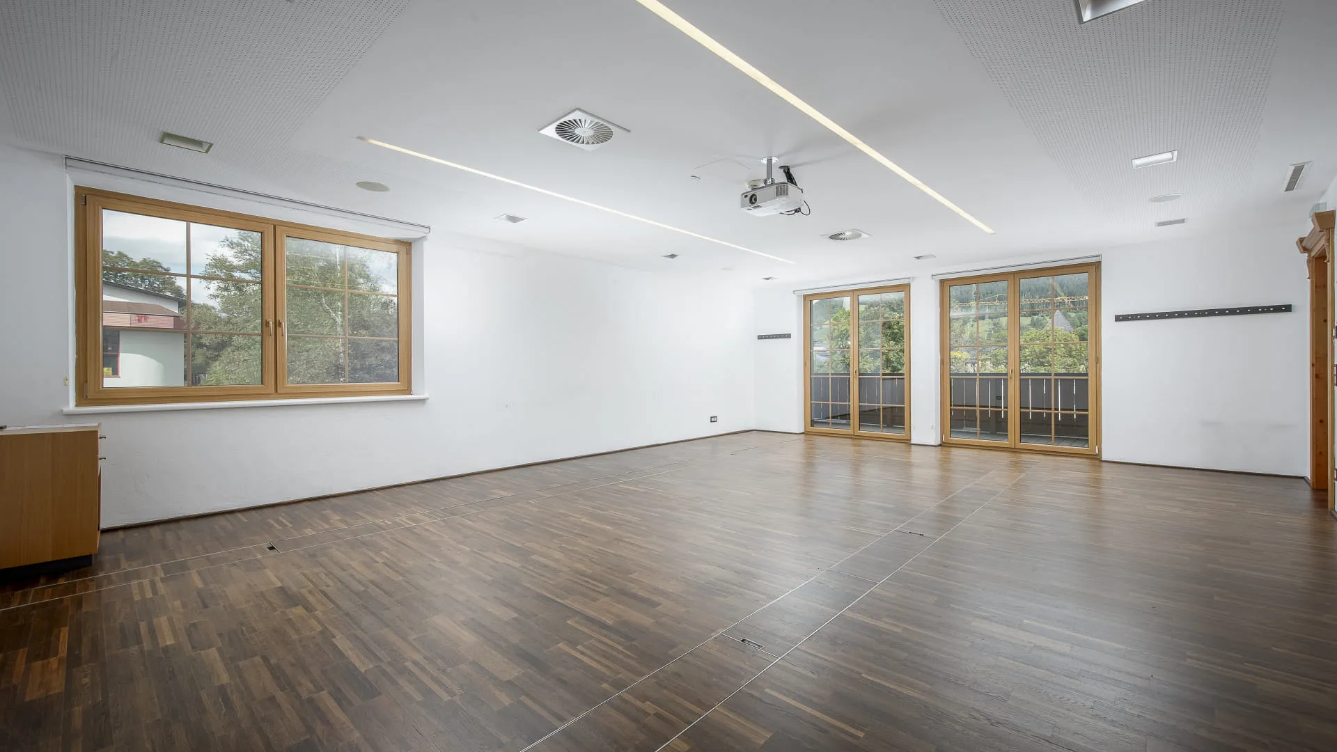 Heller Raum mit Holzfußboden und großen Fenstern