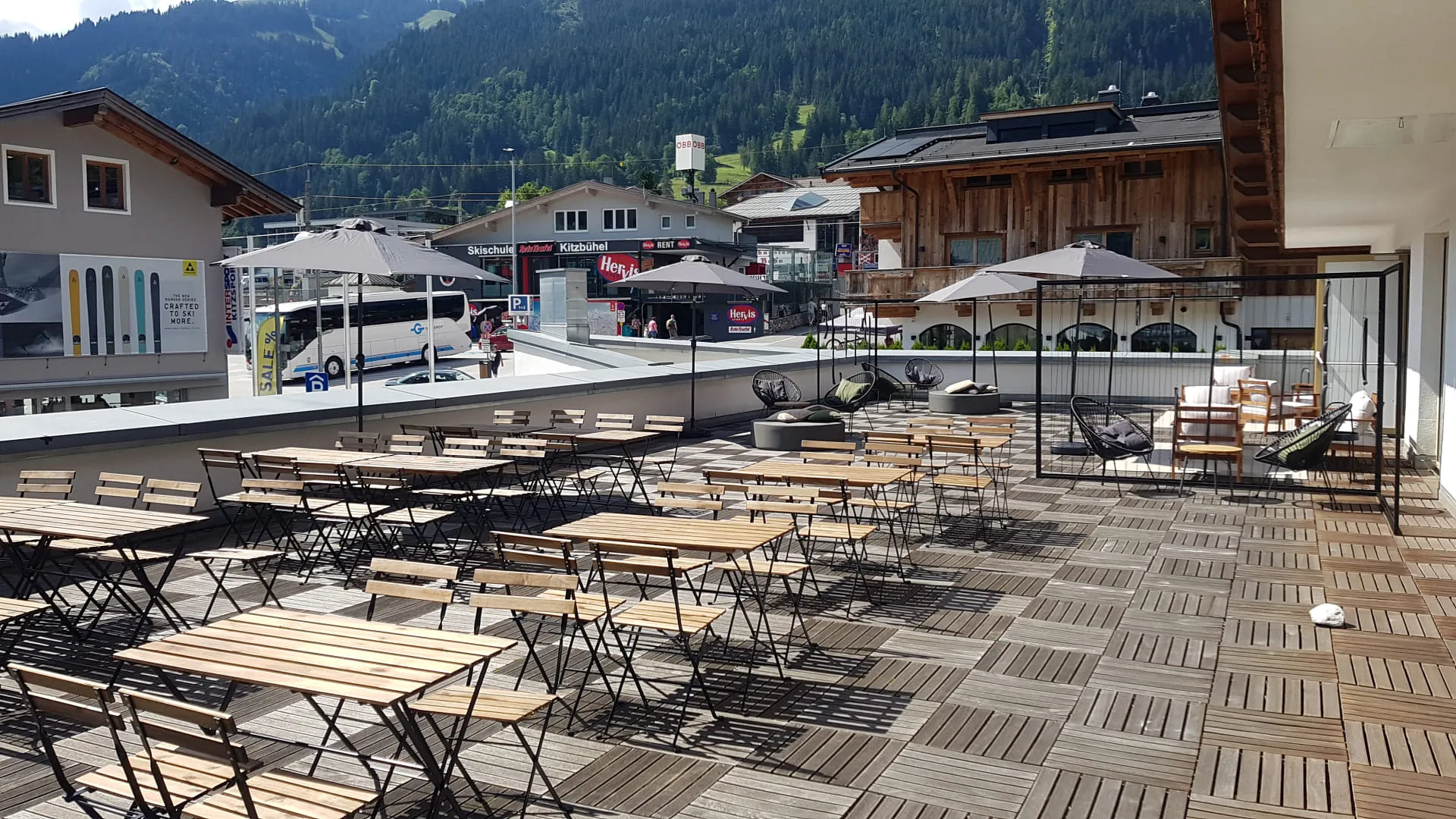 Terrasse mit Holztischen und Sonnenschirmen in den Bergen