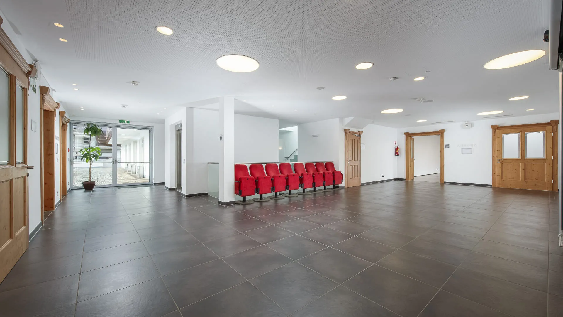 Foyer mit rotem Wartesessel und hellen Wänden