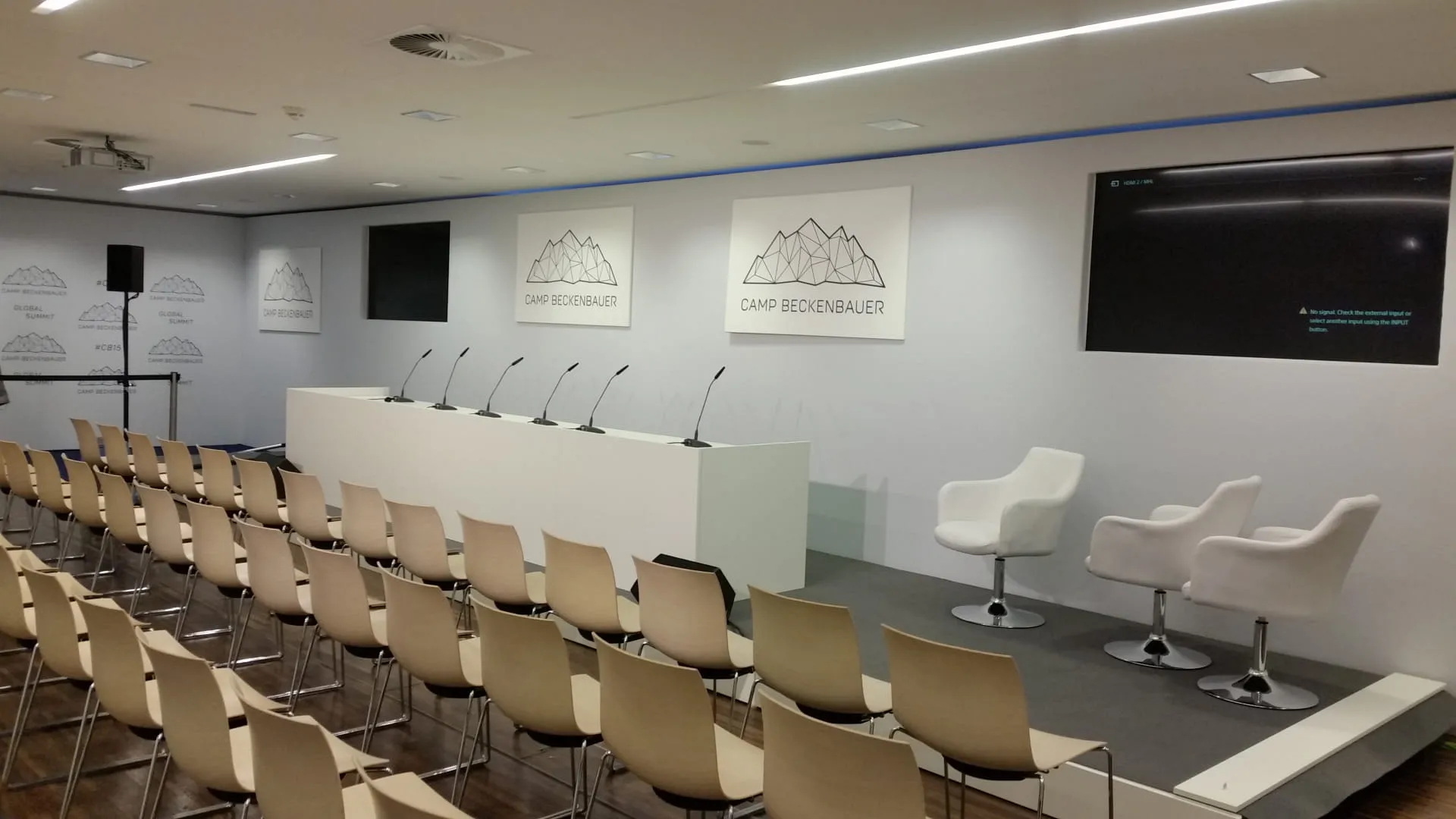 Konferenzraum mit Sitzen, Podium und Bildschirmen