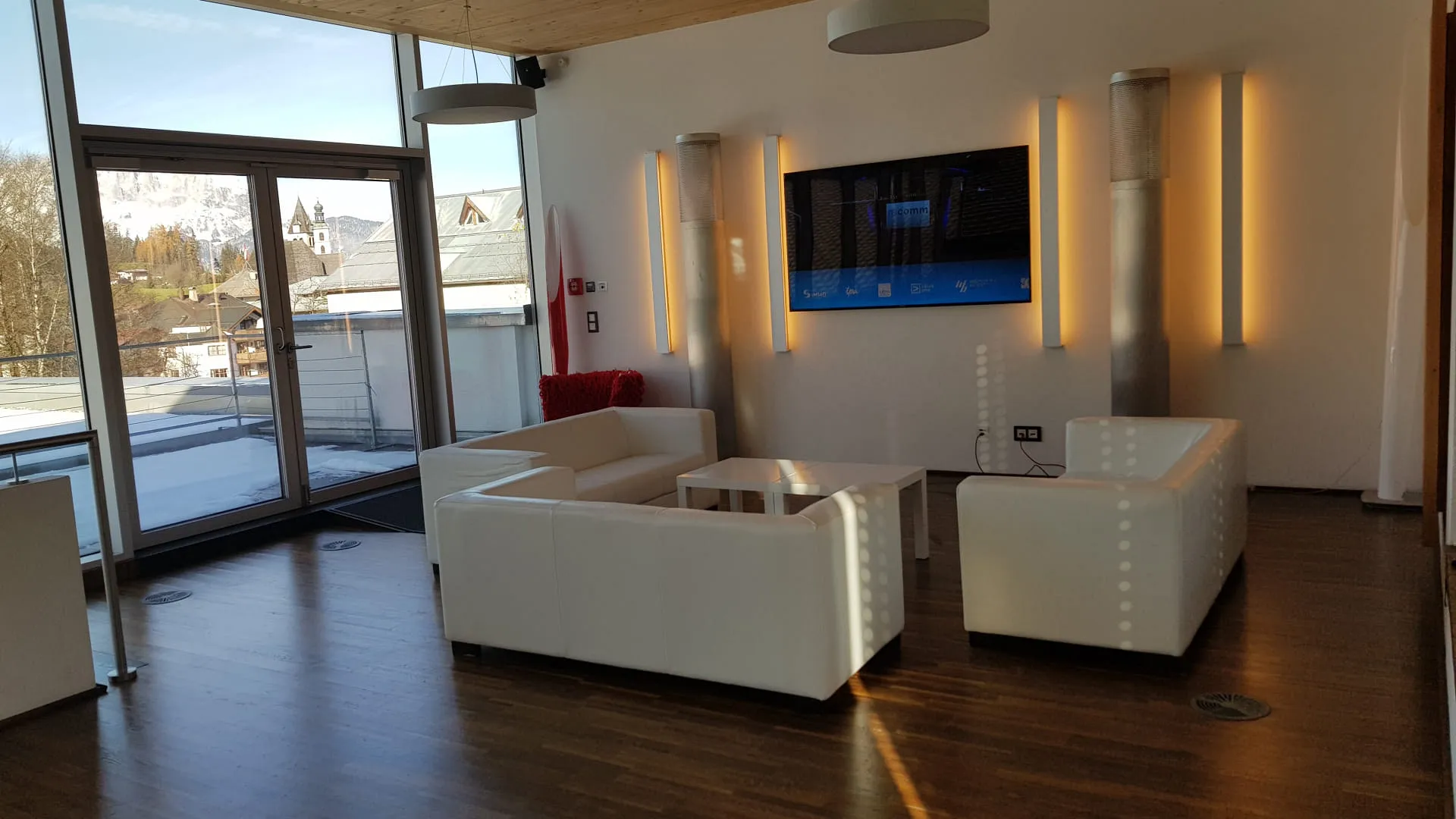 Moderne Lounge mit weißen Möbeln und großen Fenstern